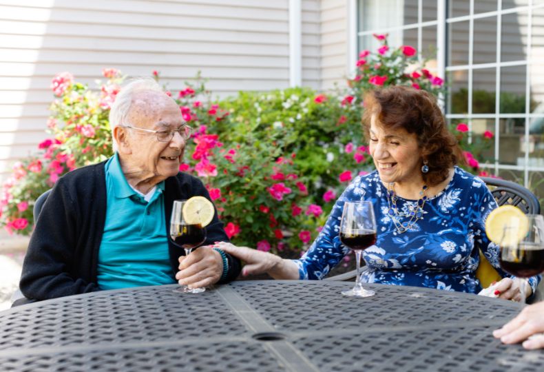 Two friends drinking wine in a courtyard.