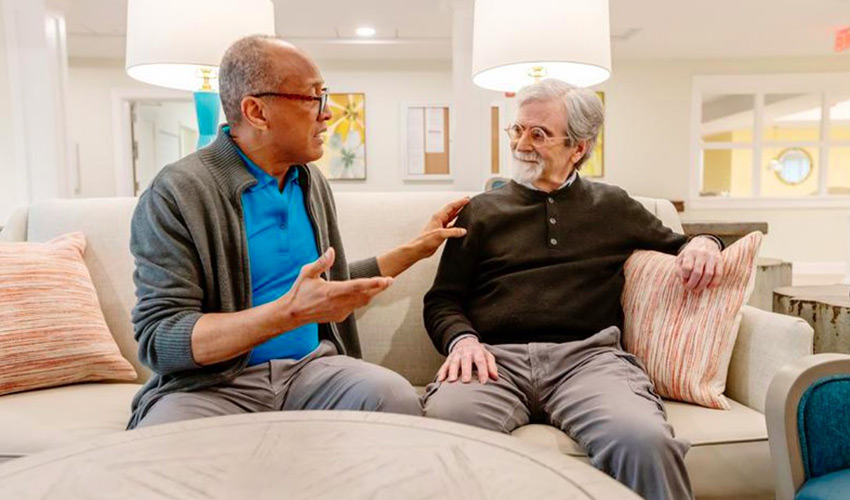 Two people sitting on the couch talking.
