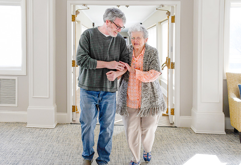 A person assisting a resident walking.