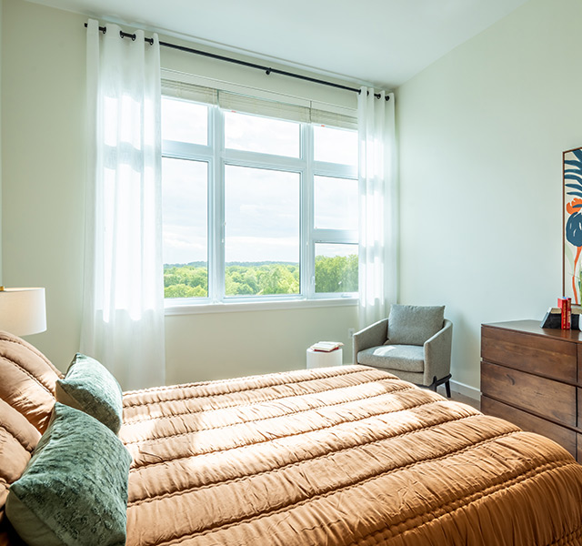 A fully furnished bedroom with a large window.