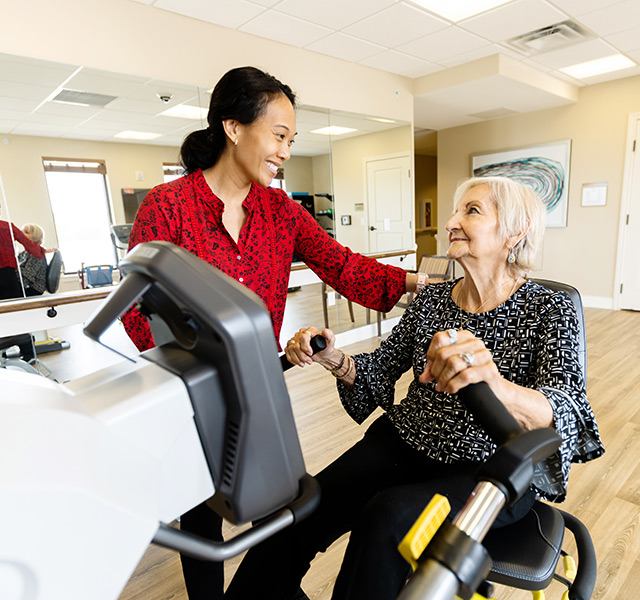 A resident working with a person on a fitness bike.