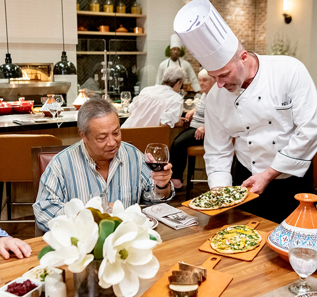 A chef is presenting food to a resident.