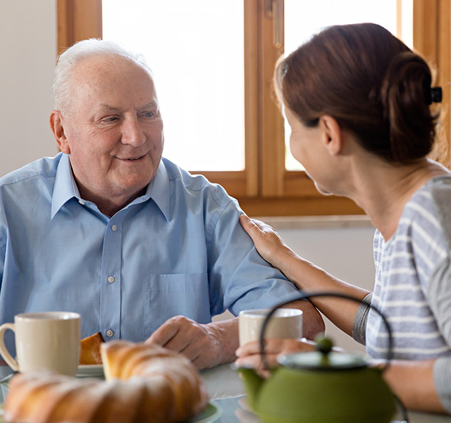 Two residents are smiling and chatting at a table eating breakfast.