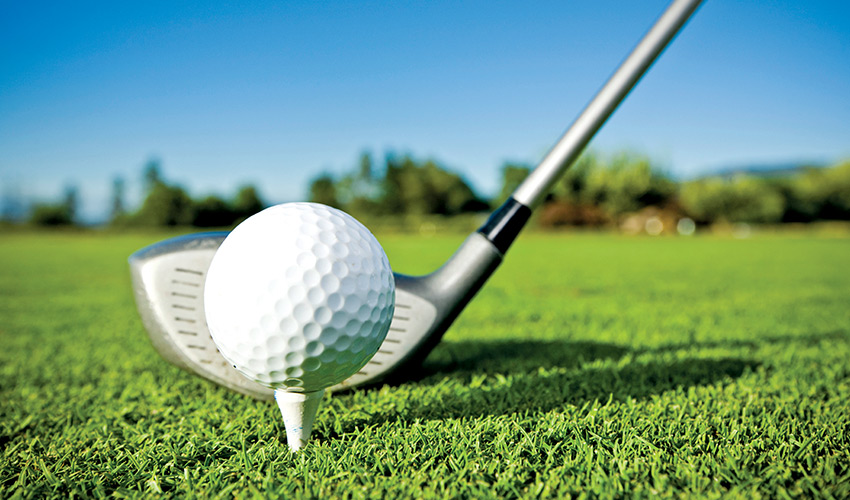 A golf club lined up with a ball on a tee.