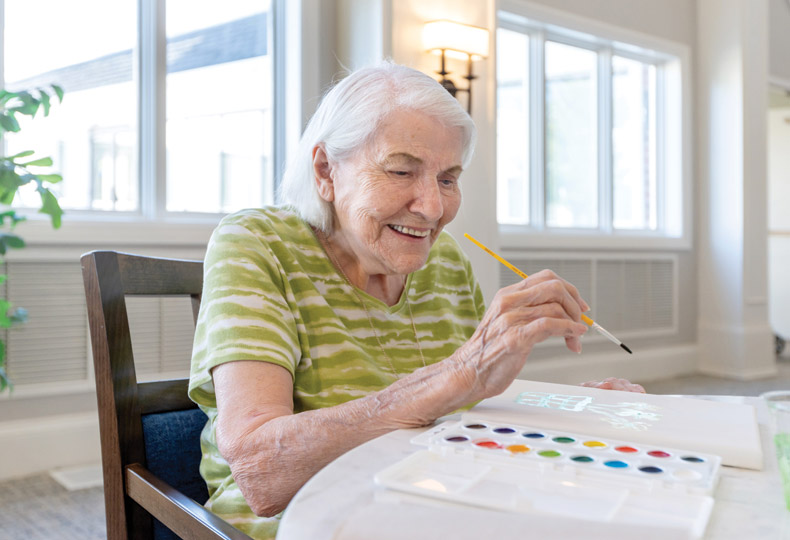 A resident is painting in an art class.