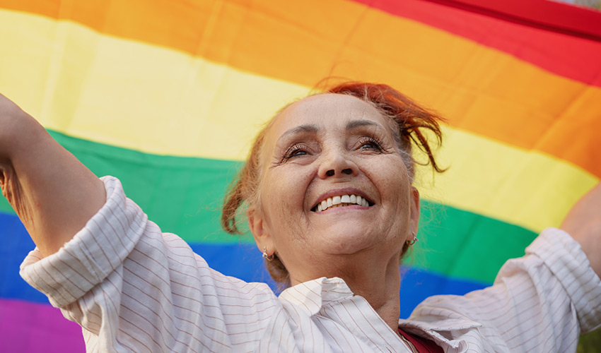 A person holding up a rainbow flag.