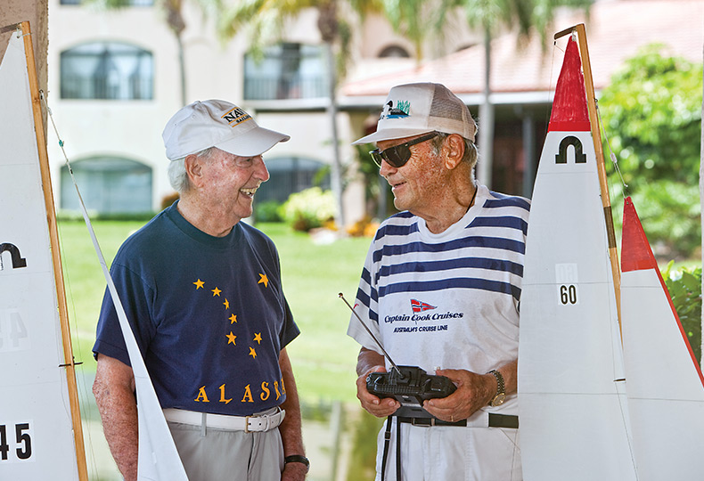 Two men are chatting about sail boats.