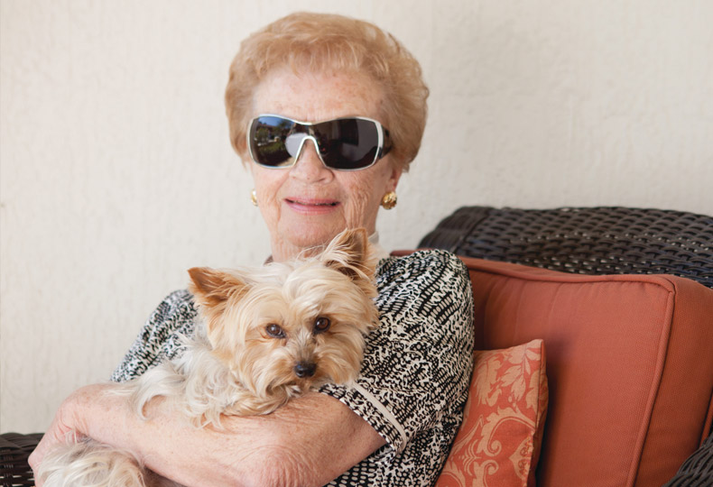 A resident sitting outside and holding their dog.