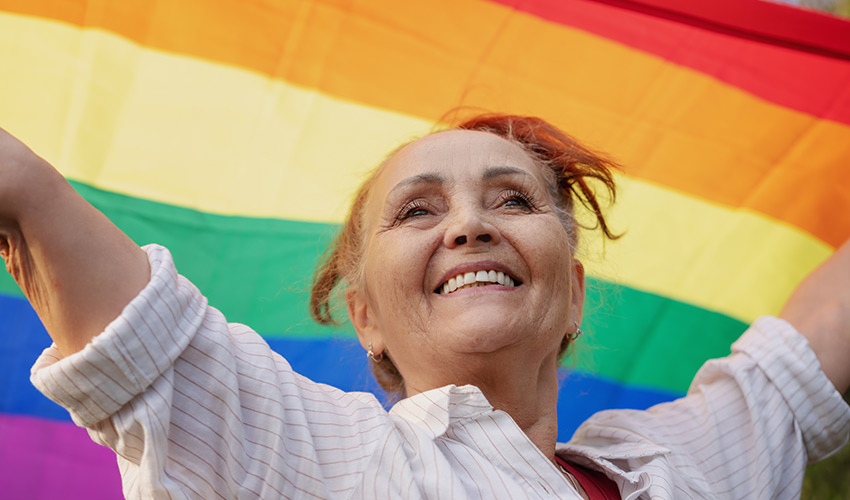 person with LGBTQ+ pride flag above their head