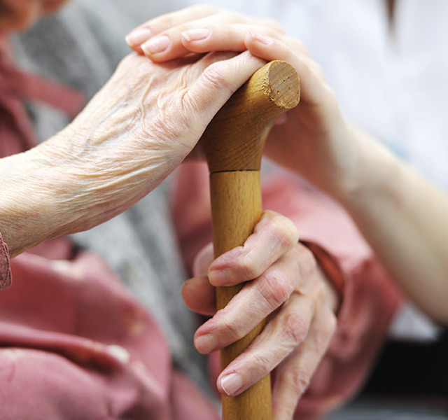 Hand over another hand holding cane.