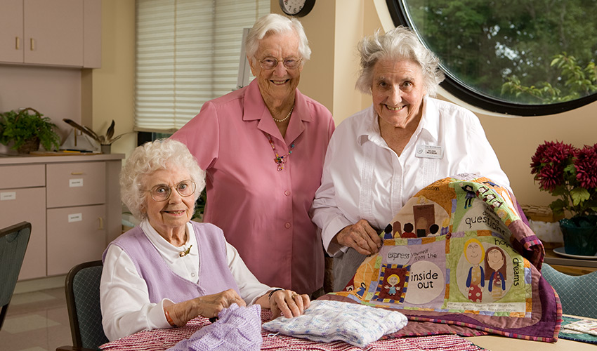 A group of ladies showing their quilts.
