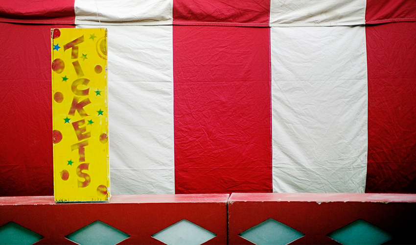 A red and white striped tent with a yellow ticket sign.