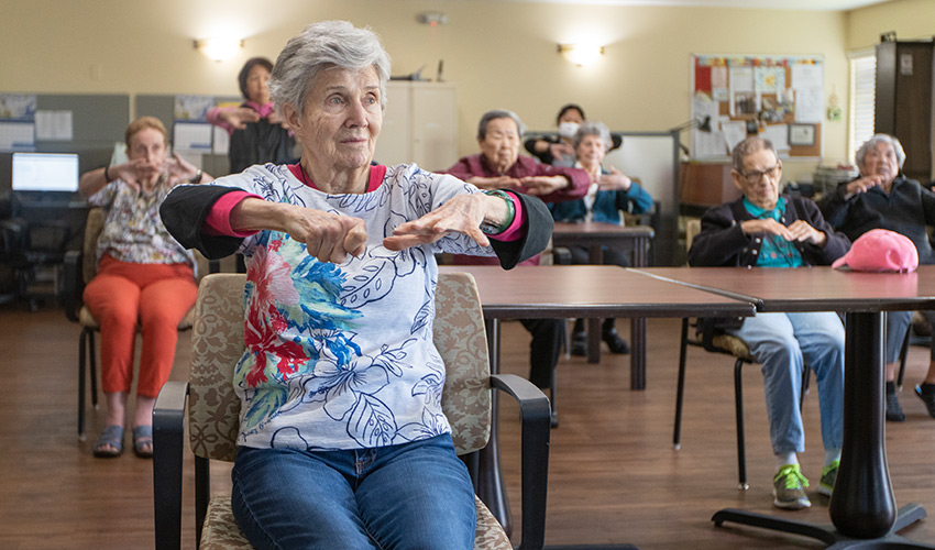 A group of seniors in a seated fitness class.