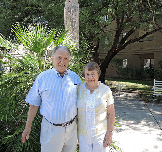 Two residents are standing together in a courtyard outside.