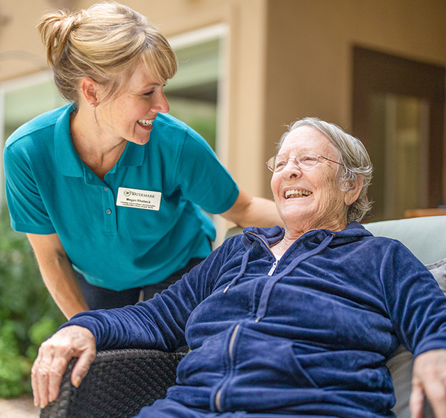 A resident is sitting outside with a caregiver.