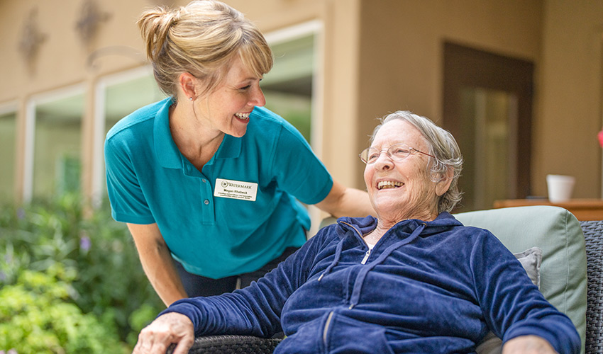 A caregiver checking in on a person in a chair.