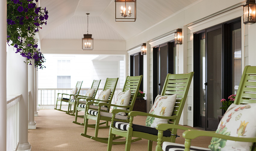 A porch lined with green rocking chairs.