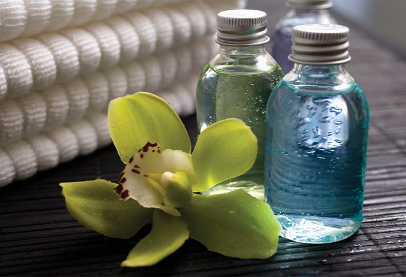 The Fountains at the Albemarle Indulge Salon & Spa A vibrant green floral next to bottles of botanicals atop a wooden table.