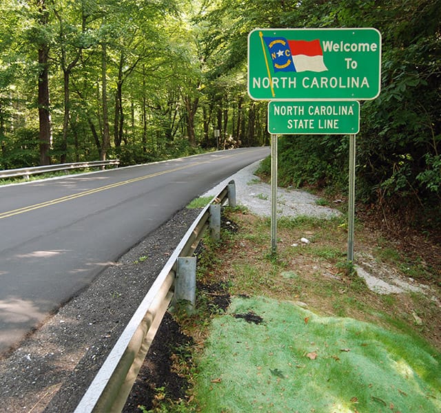 The Fountains at the Albemarle The Neighborhood - North Carolina A 'Welcome to North Carolina' sign along the side of the highway crossing the state line.