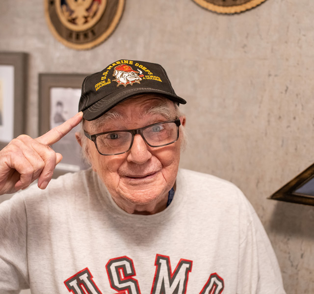 Veteran resident wearing a baseball cap saluting.