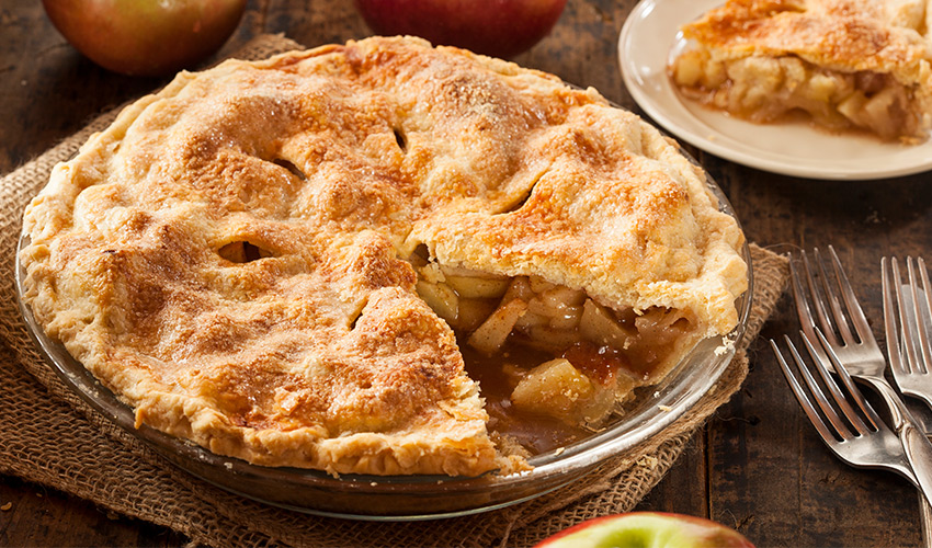Apple pie with a slice cut out and on a plate on the side.