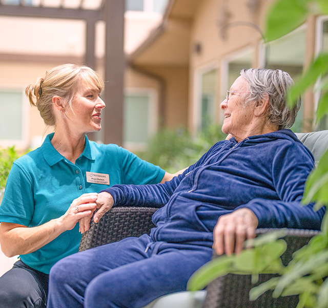 a team member kneeling and speaking to a guest sitting down outside