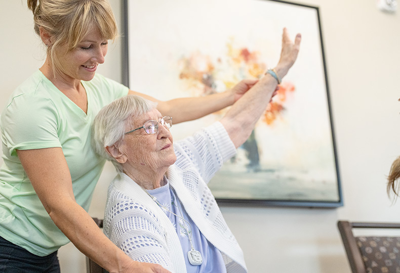 A caregiver helps a resident stretch their arm.