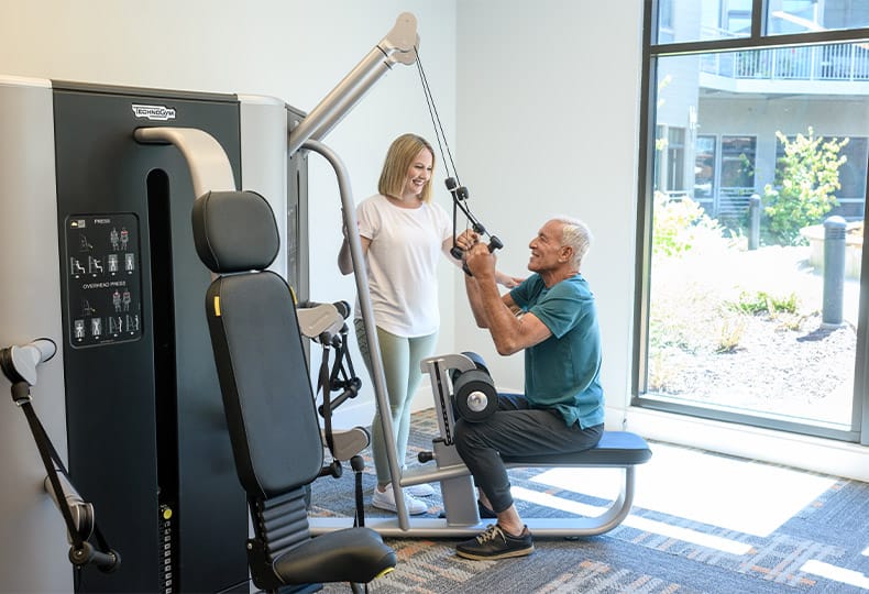 Residents enjoying the fitness room and using machines.