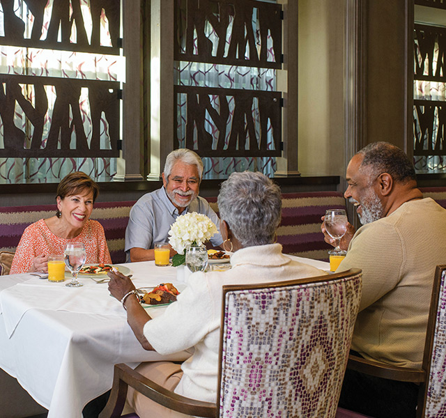 four residents sitting at a dining table enjoying dinner