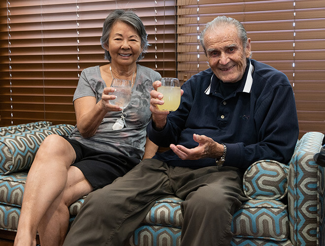 couple is sitting on sofa smiling with drinks in hands