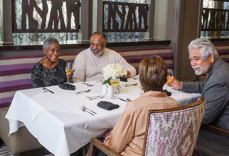 A group of residents seated in a booth in one of the on-site dining establishments at The Preston at the Park Cities