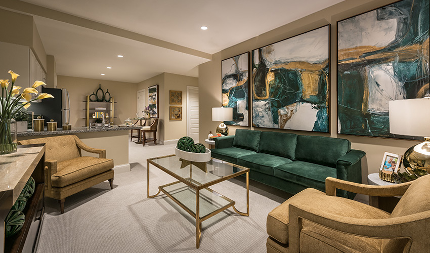 A beautifully furnished model loving room with tones of gold and green.