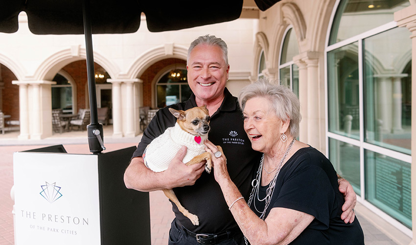 A resident and her dog with a Watermark associate at the entrance.