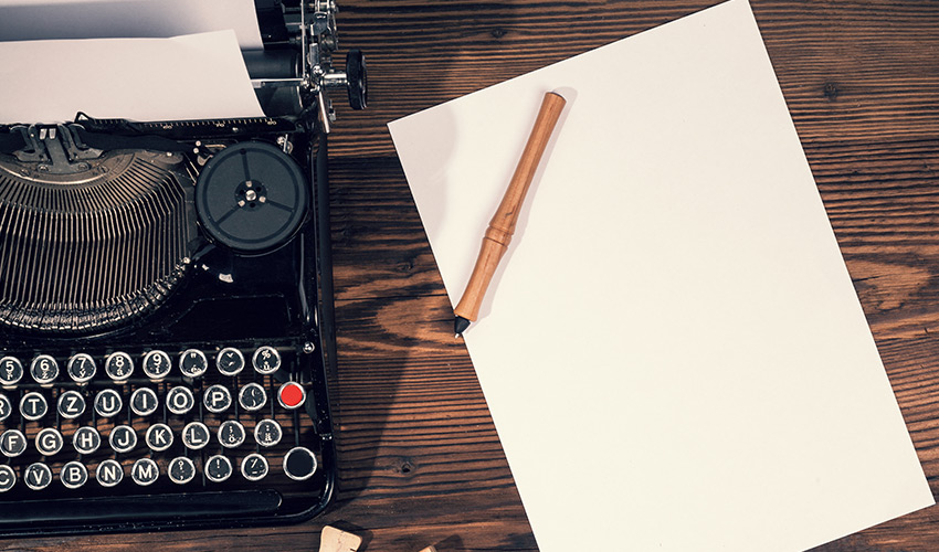 A typewriter with a piece of paper next to it on a desk.