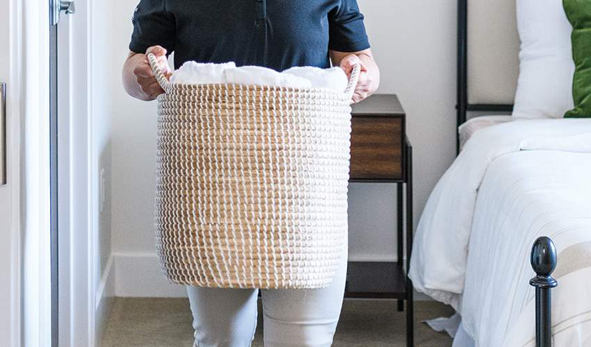 A close up of housekeeping carrying a laundry basket.