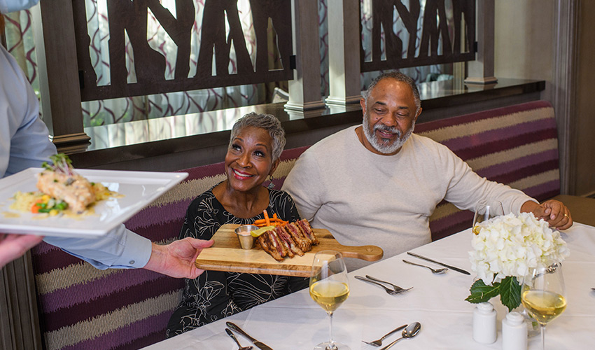 An african american couple being served dinner in the dining room.