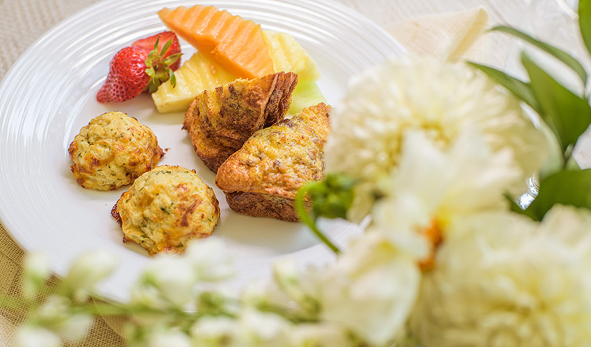 A plate with small bites of food garnished by fruit.