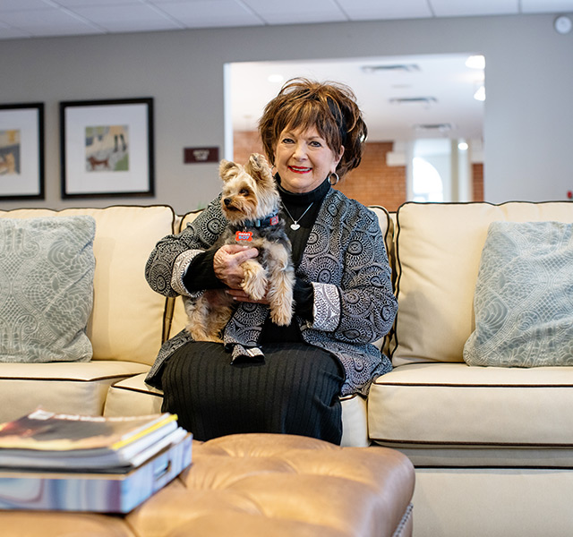 A person sitting on the couch with a dog.