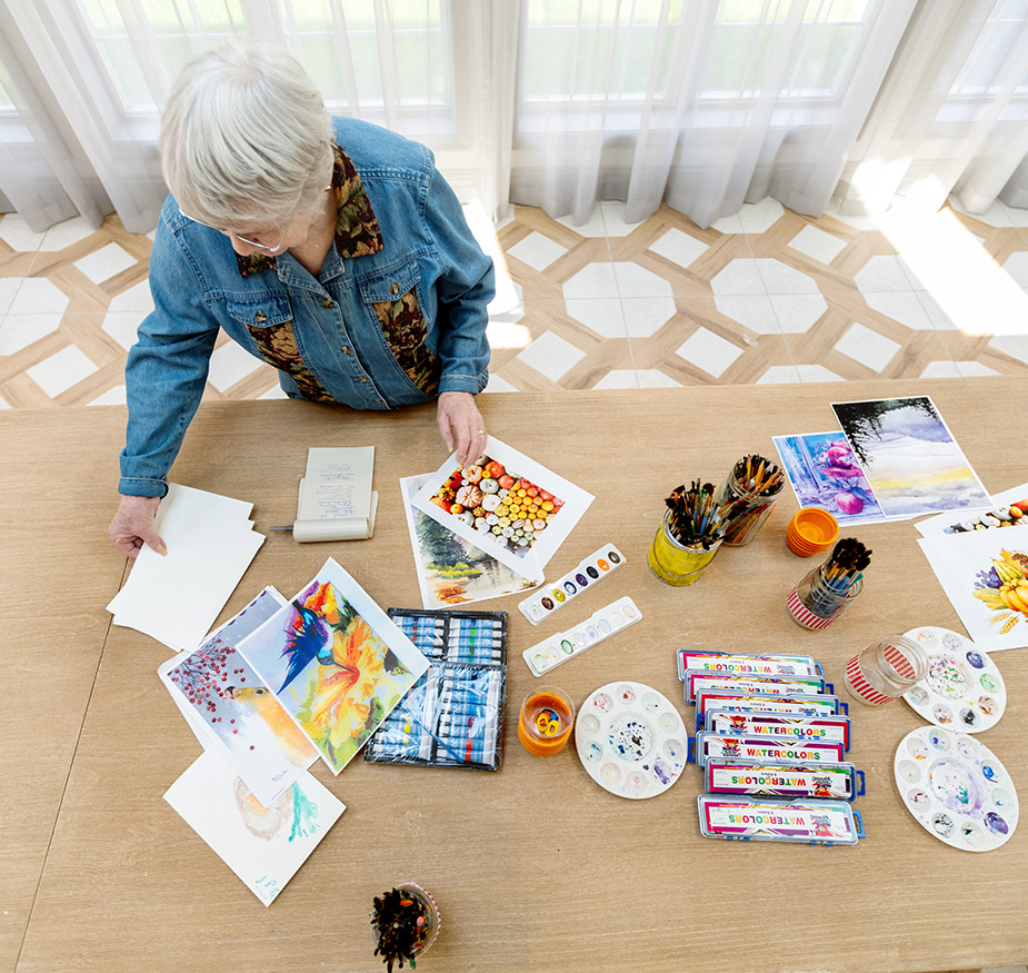 A person at a table full of painting supplies.