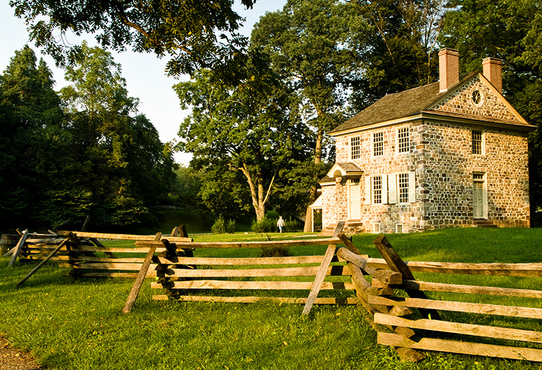 An old stone house at valley forge with a split wood fence.
