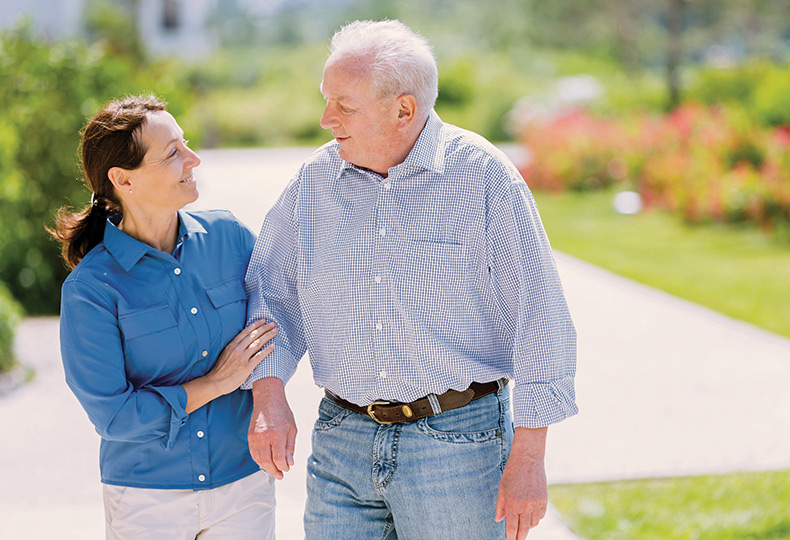 A resident is walking with their caregiver.