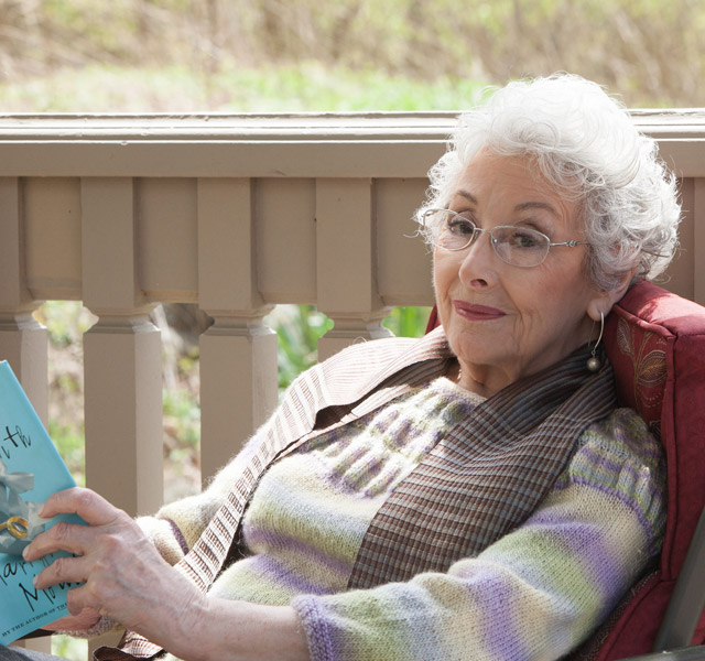 A resident is on the porch reading a book.