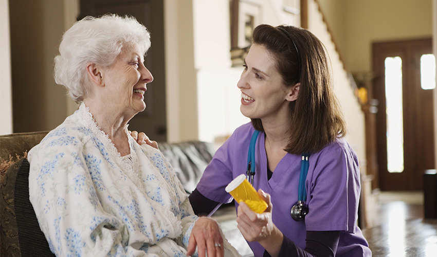 nurse talking and handing medication to a resident