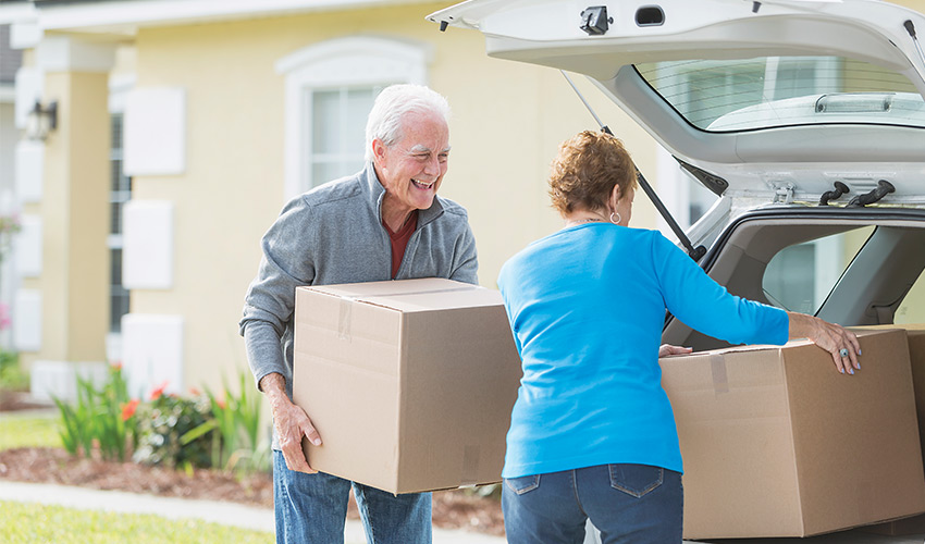 two people loading the trunk of a car with boxes