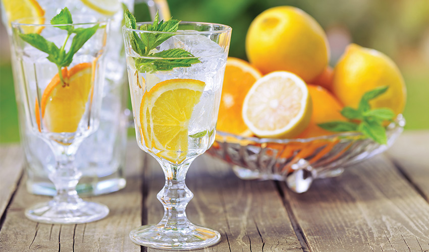 glass of water with lemons and a bowl of lemons