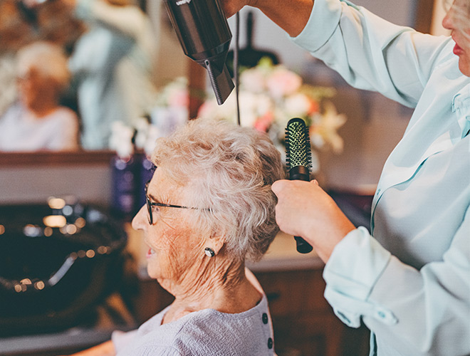 A resident is having their hair styled at the salon.