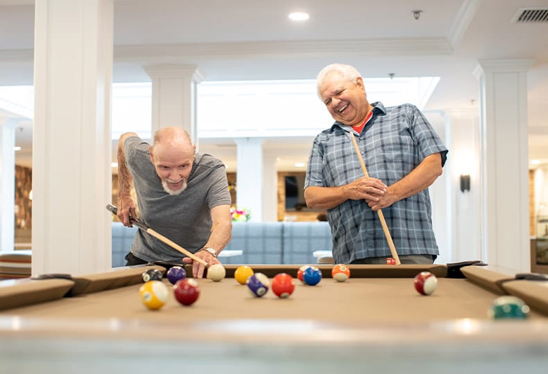 Two residents are playing a game of pool.