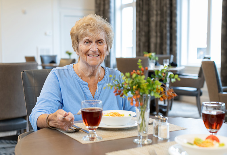 A resident is eating in the dining area at The Watermark at St. Peters.