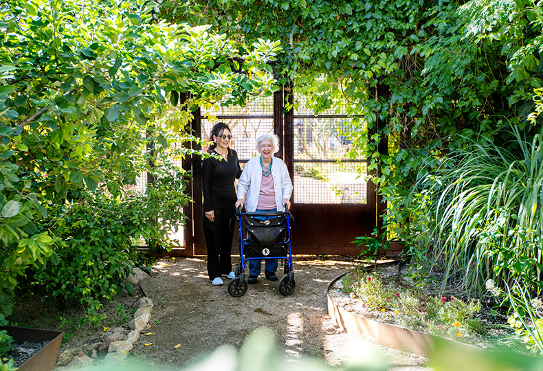A resident is walking with a caregiver.