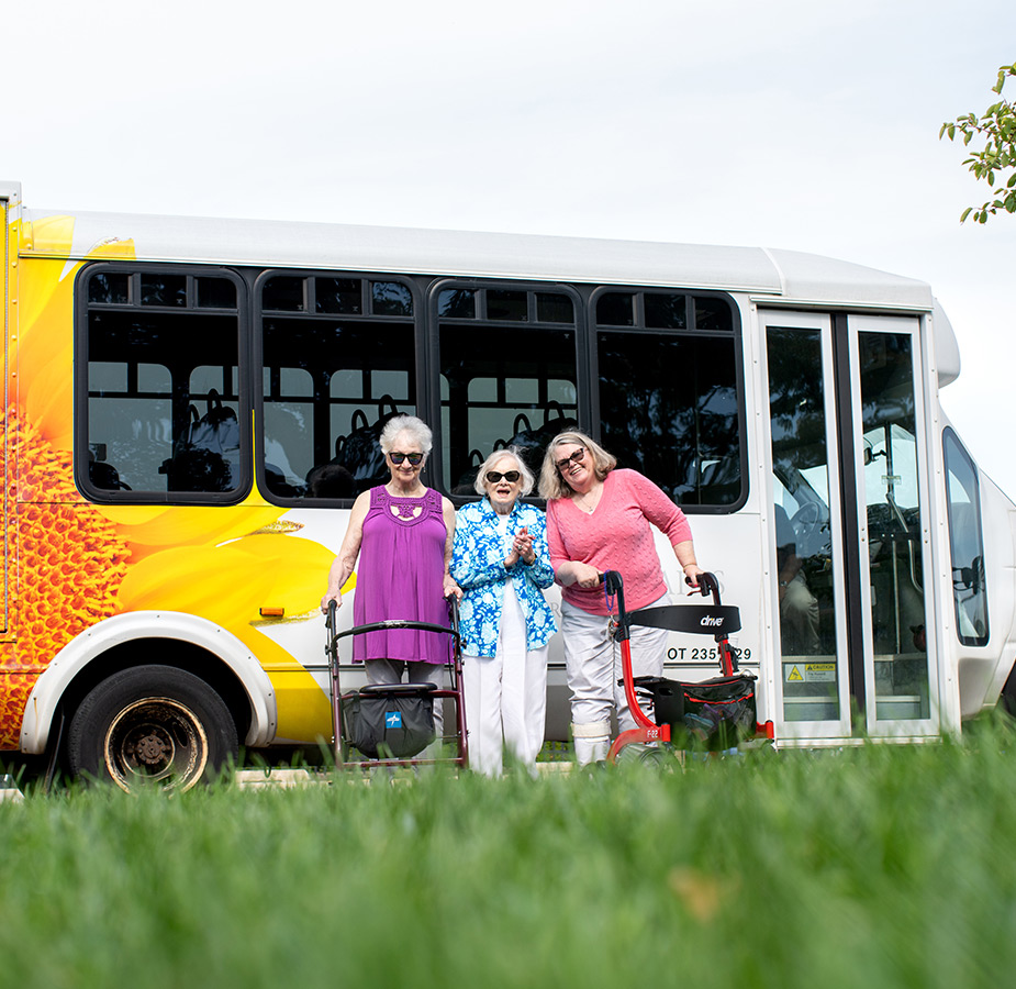 Three residents are standing next to the bus.
